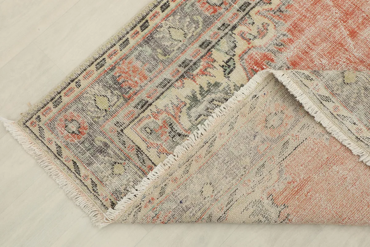 Corner of the rug folded back to show the pile and foundation structure.