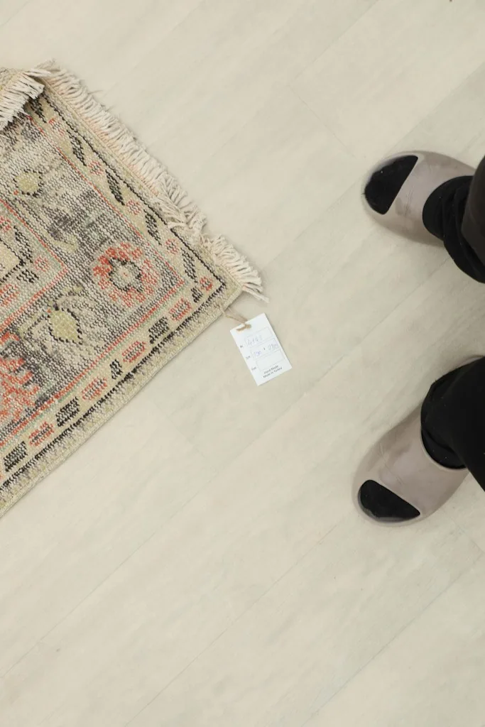 A small corner of the rug next to feet, indicating its scale and texture.