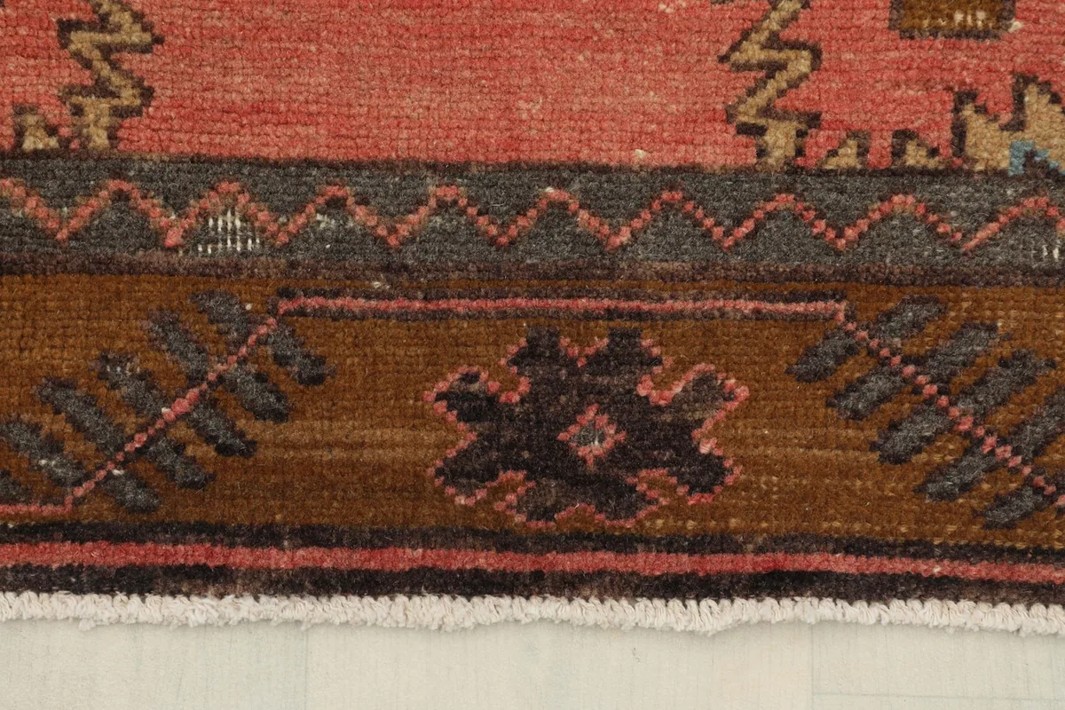 Close-up of the brown border with small geometric motifs and the rose field