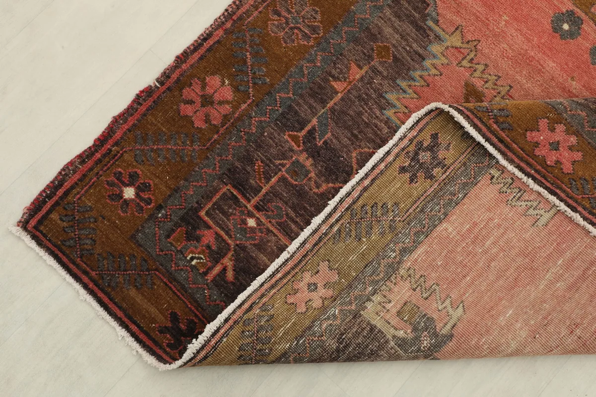 Corner of the rose rug folded back, showing the cotton foundation and reverse side