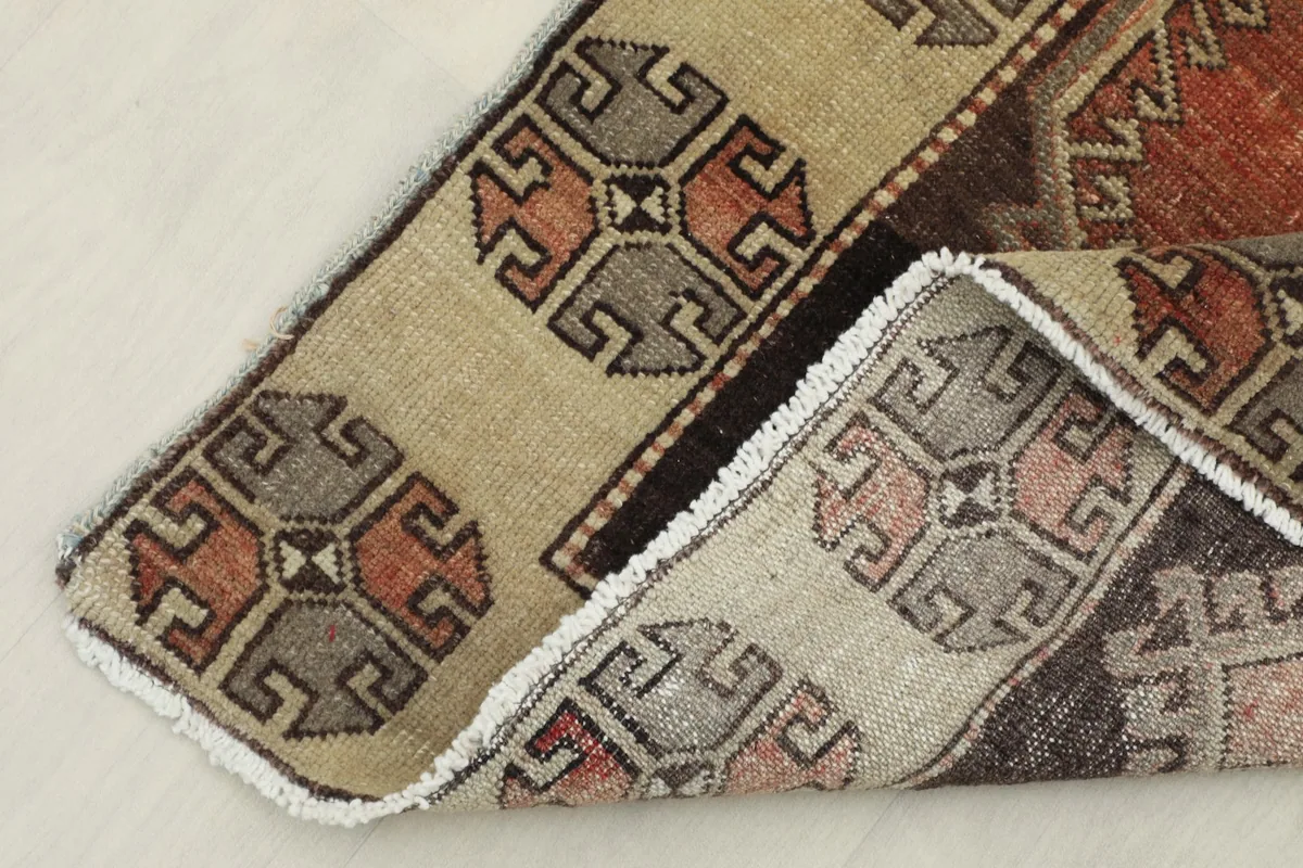Corner of the rug folded back, revealing the reverse side of the hand-knotted wool pile and cotton foundation.