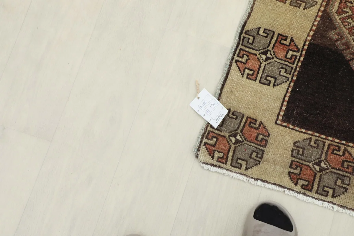 Corner of the rug with a small tag, demonstrating the scale with a foot partially visible.