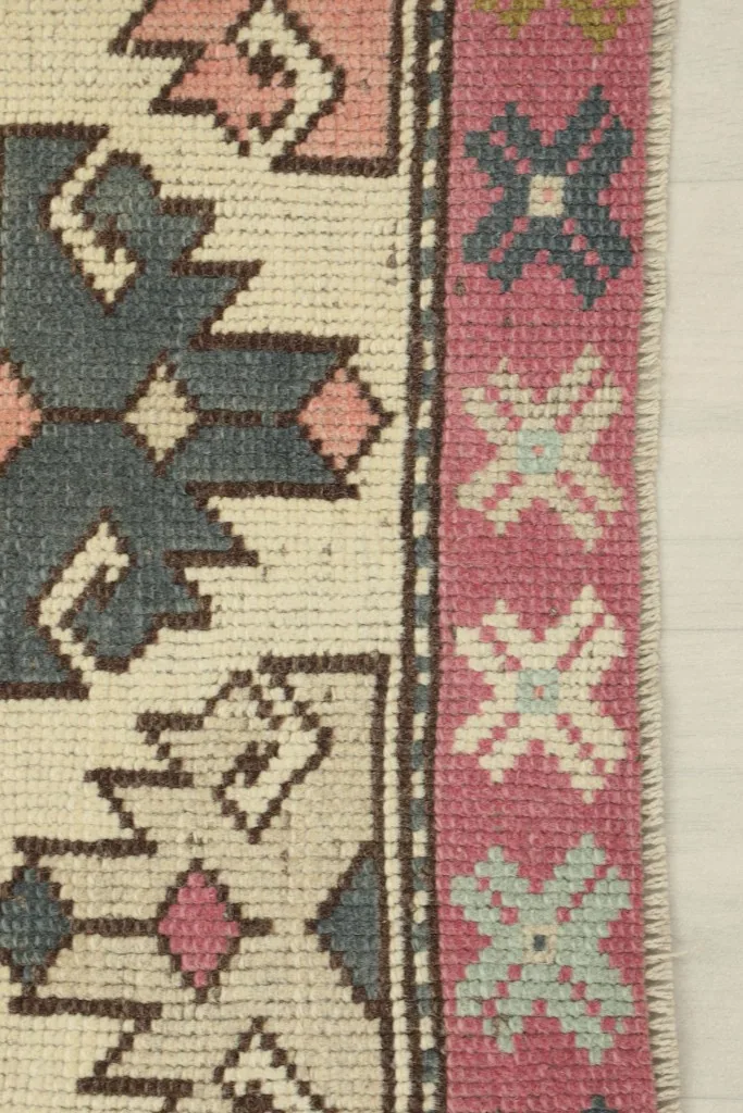Close-up of the rug's side border, showing the tight knotting and the distinct rose and blue cross patterns.