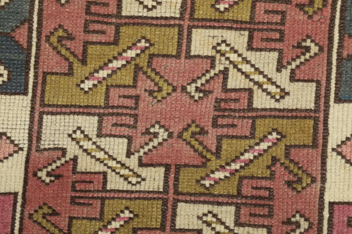 Macro shot of the hand-knotted wool pile, revealing the texture and specific color blending of the motifs.