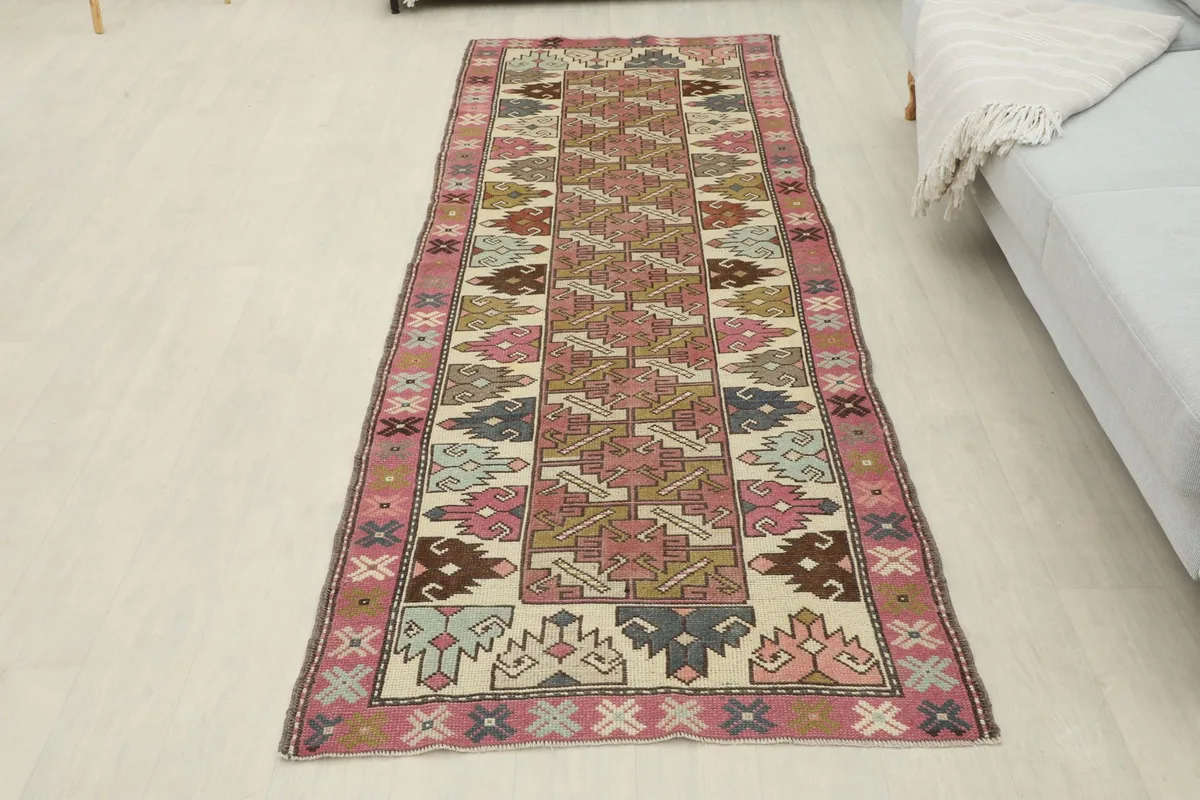 Full overhead view of the vintage runner rug, laid out to display its complete rose and ivory geometric design.