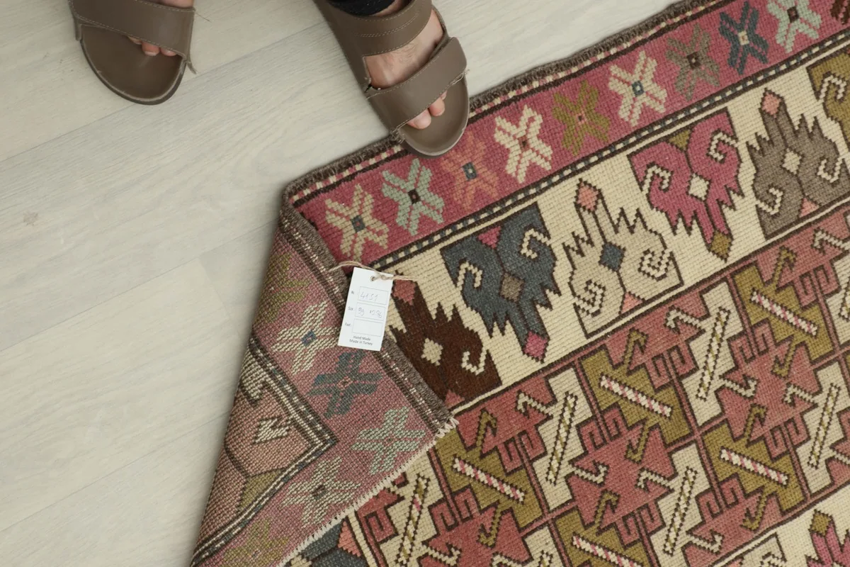 Overhead detail showing the rug's corner with a tag, providing a sense of scale with feet in the frame.
