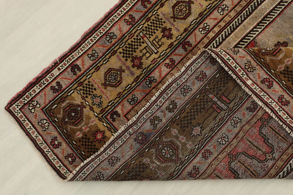 View of the rug folded back to show the cotton foundation and the reverse side of the pattern.