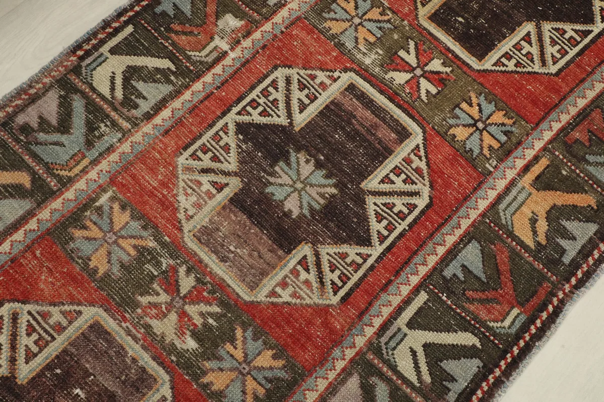 Close-up detail of a central octagonal geometric medallion in brown and beige tones on the red field