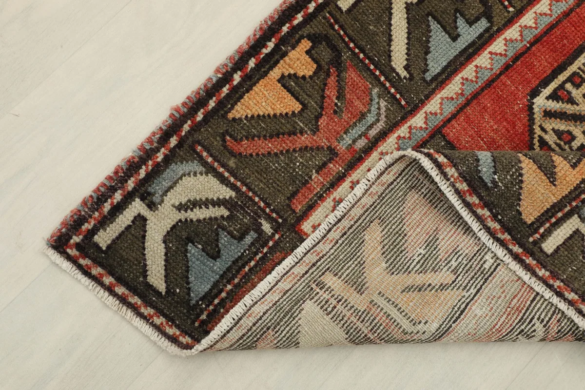 Corner of the runner rug folded to reveal the hand-knotted cotton foundation and reverse side of the pile