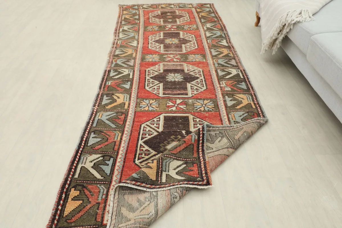 Runner rug partially folded, showing its flexibility and the back of the rug laid out in a room