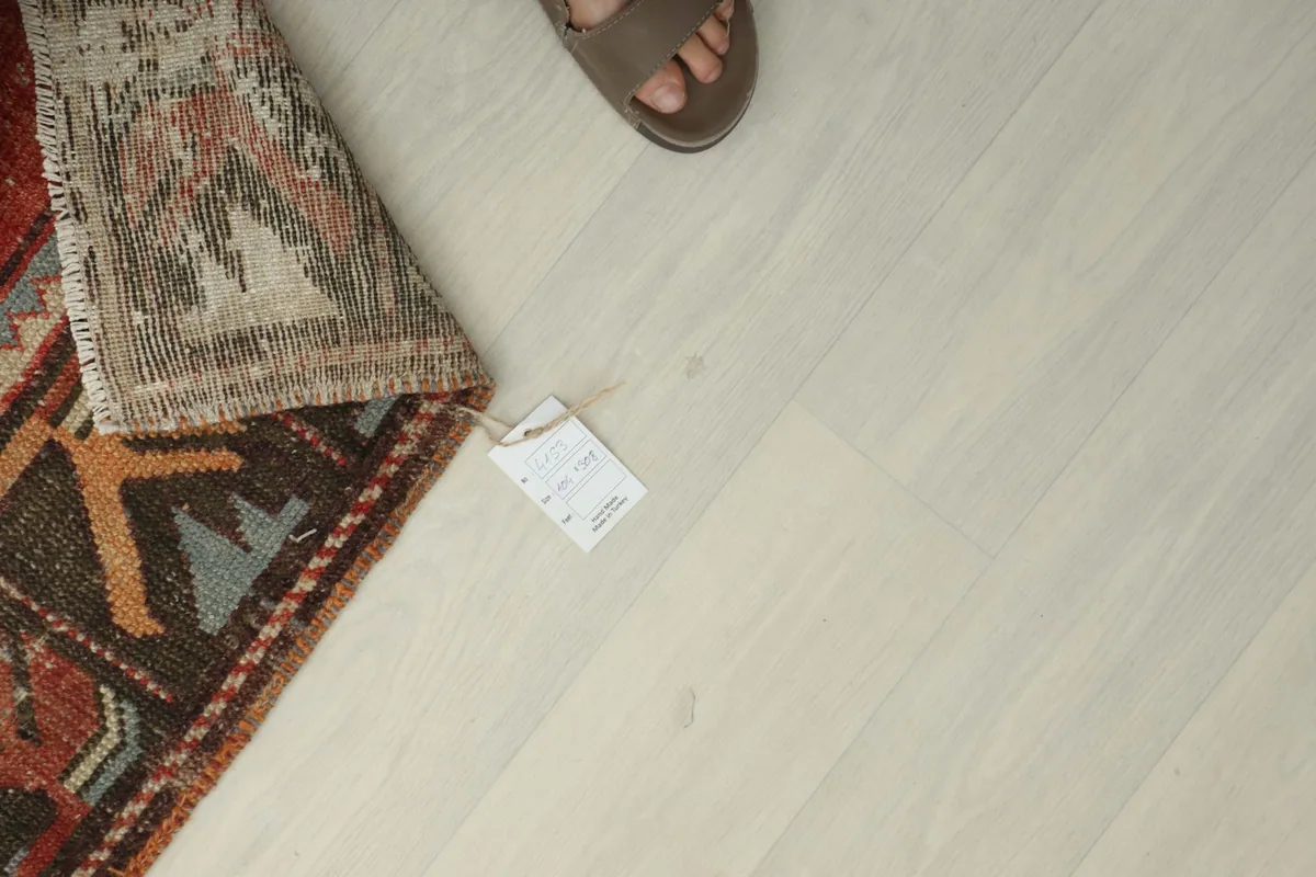 Overhead view showing the rug's tag and a foot for scale, emphasizing the rug's size and authenticity