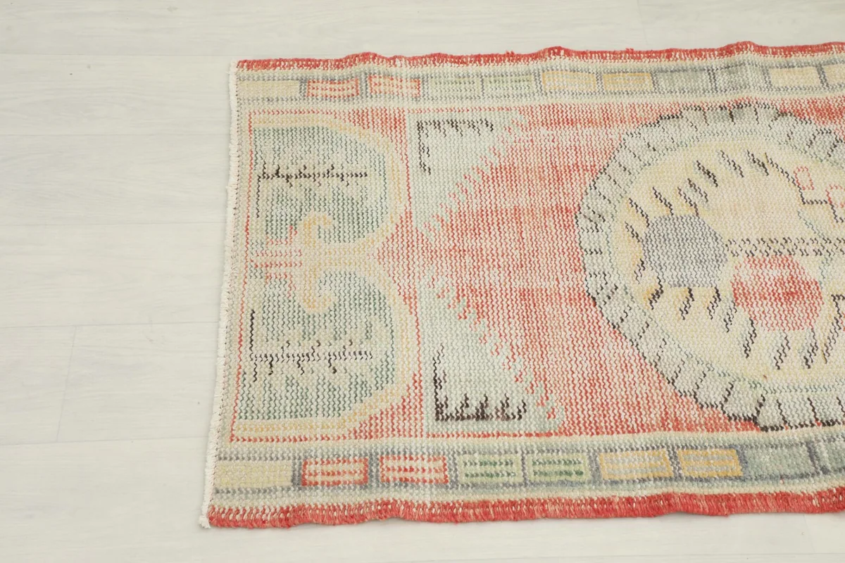 Detailed view of the rug's side pattern featuring rust, ivory, and beige tones with geometric motifs.