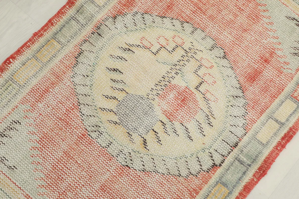 Macro view of the central ivory medallion with gray and rust accents, highlighting the wool texture.