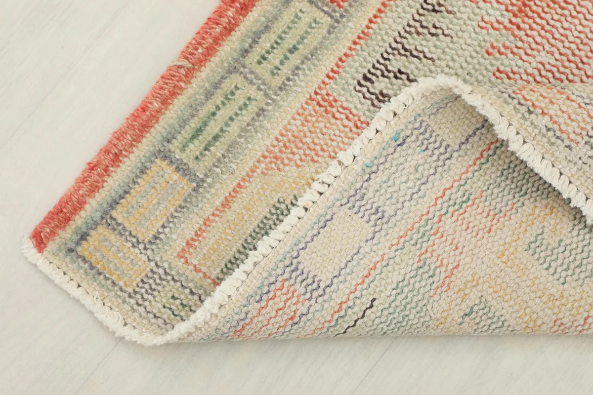 Corner of the rug folded to reveal the cotton foundation and the reverse side of the hand-knotted wool pile.
