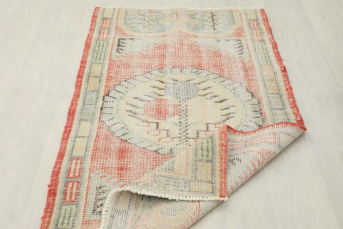 The vintage Anatolian rug partially folded, showing its flexibility and the consistent hand-knotted quality.