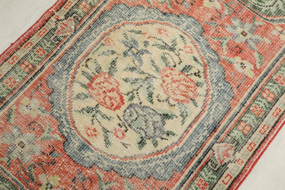 Detailed view of the central ivory and blue floral medallion with rust and green accents