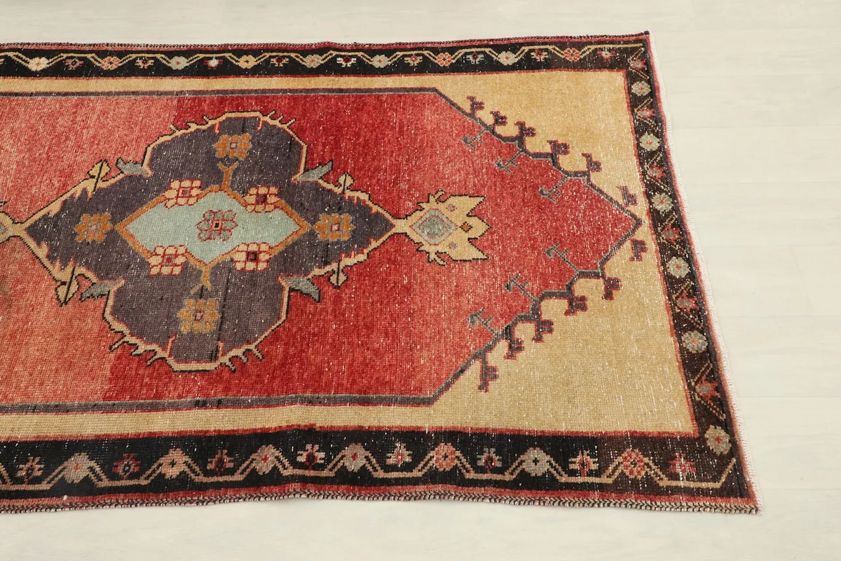 Close-up of the rust field, navy medallion, and black border of the vintage Anatolian runner