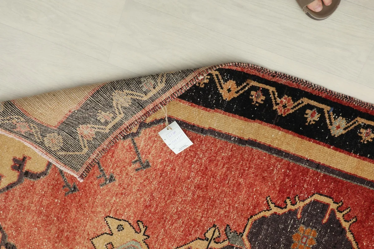 Close-up of the rug's back with a tag, showing the hand-knotted wool pile on a cotton foundation