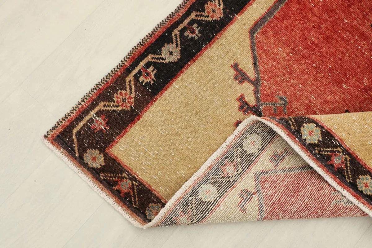 Corner of the runner rug folded back, revealing the reverse side and cotton foundation