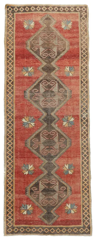 Full overhead view of the red geometric Anatolian runner rug on a white background.