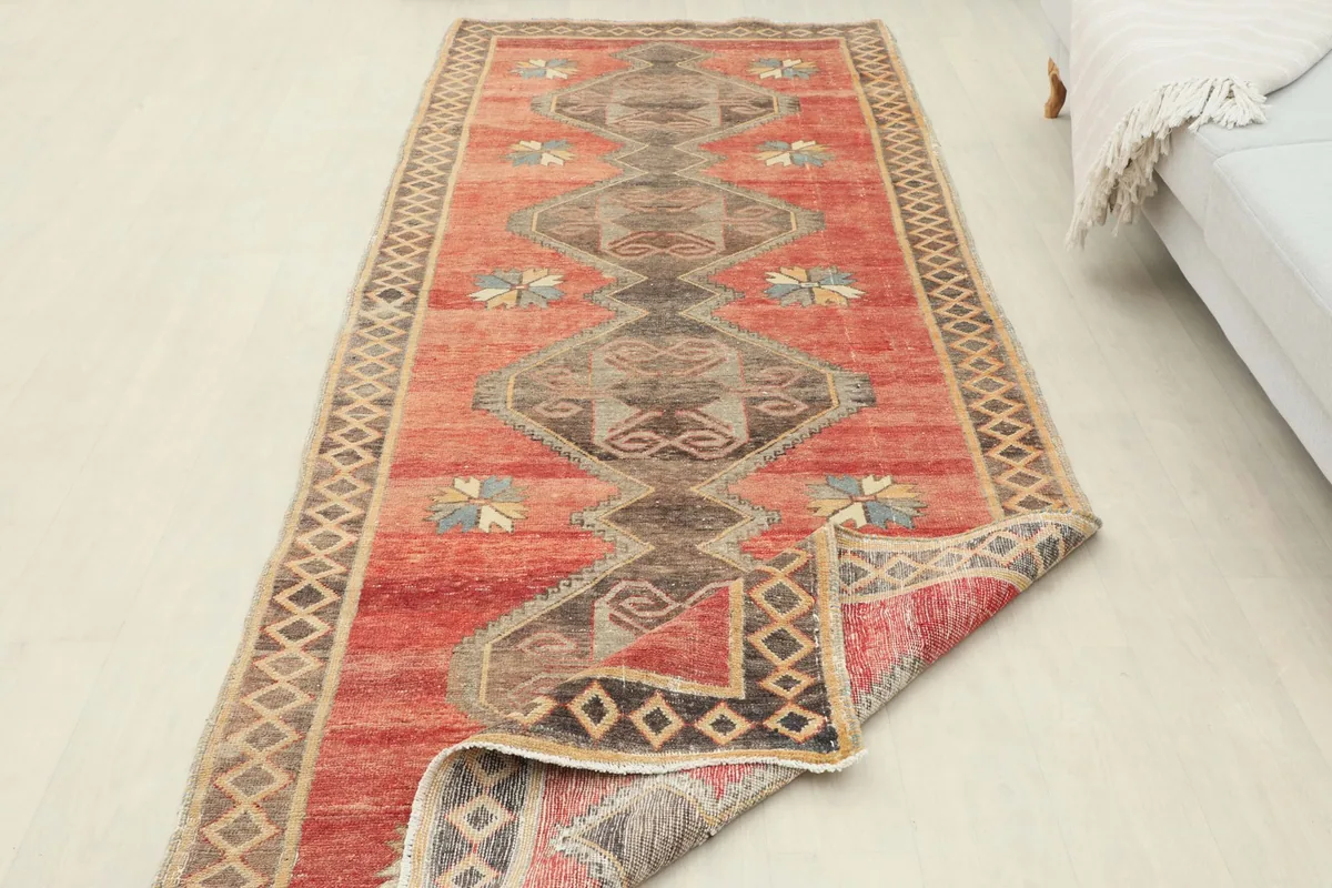 Full length view of the runner rug in a room, with one end slightly folded.