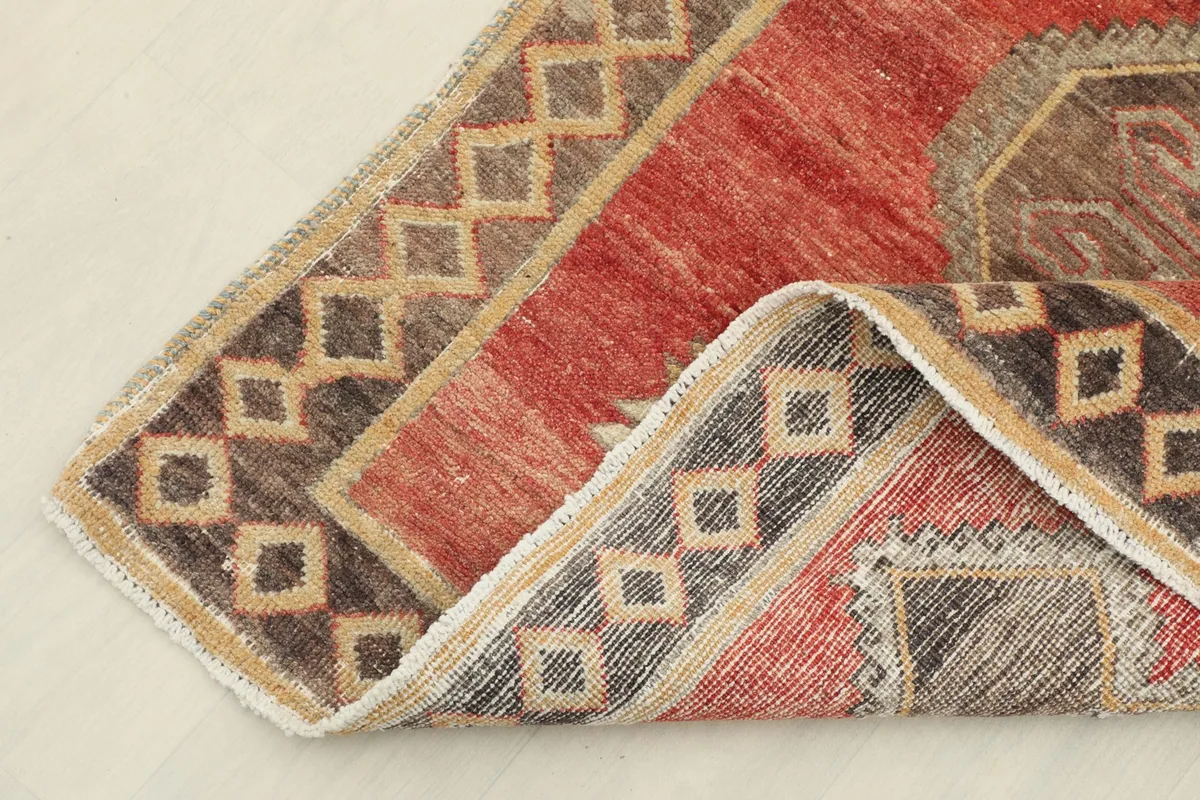 Corner of the rug folded back, revealing the hand-knotted construction and cotton foundation.