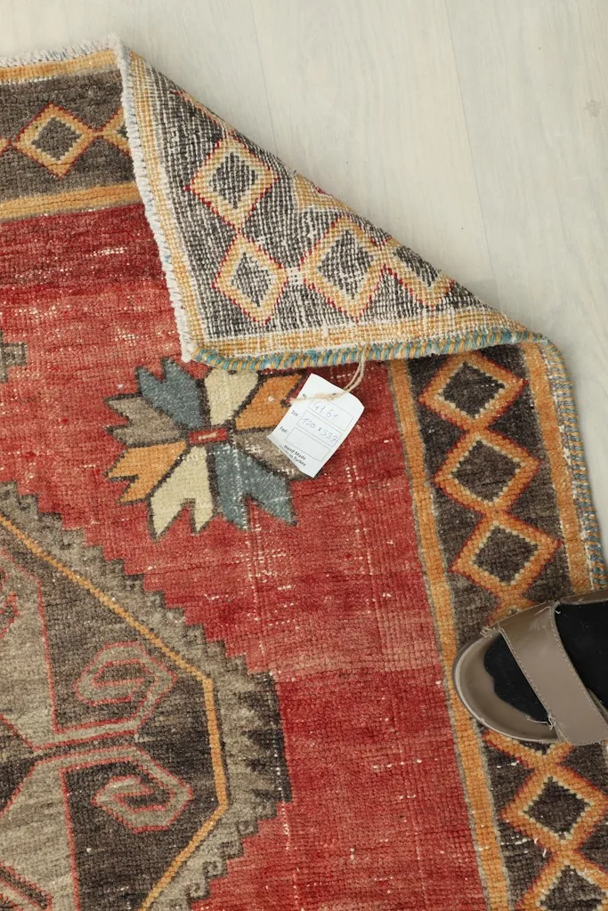 Overhead view showing the rug's corner with a tag and a pair of shoes for scale.