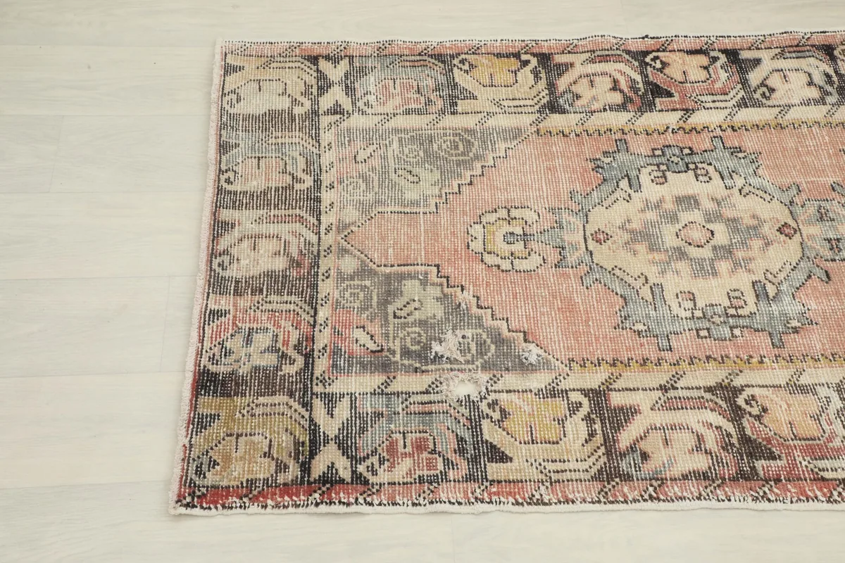Corner view of the vintage Anatolian runner rug, highlighting the dark brown border and faded colors