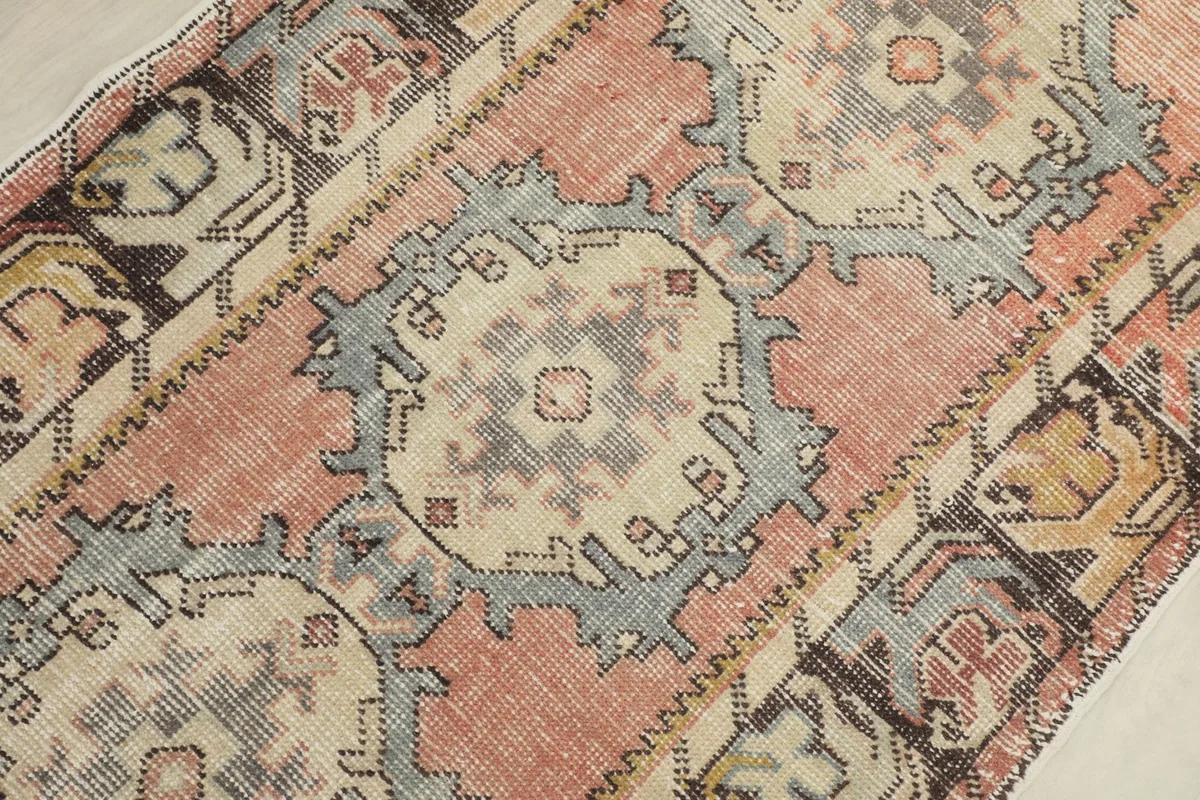 Detailed view of the central geometric medallion in blue and beige on the rust field