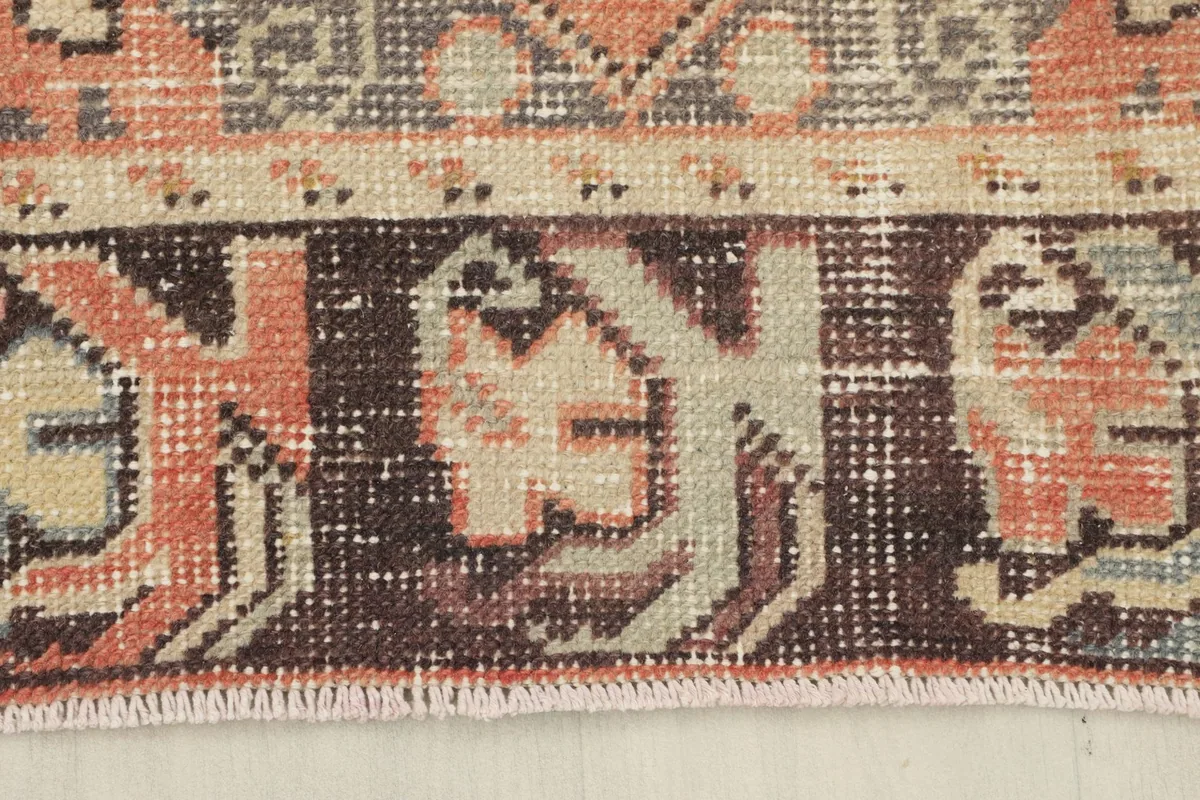 Detail of the dark brown border with tribal-inspired motifs and the rug's edge