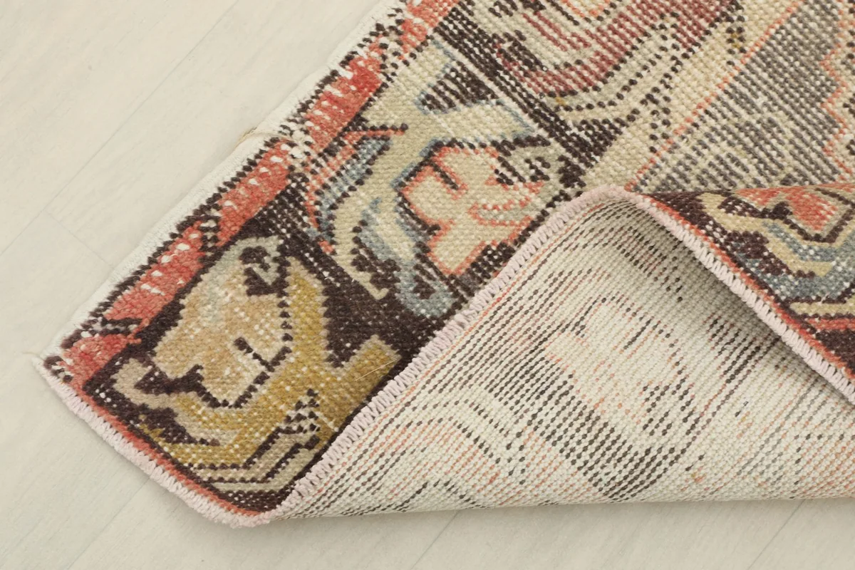 Corner of the runner rug folded back to show the cotton foundation and hand-knotted construction