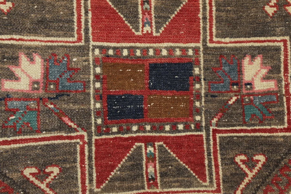 Extreme close-up of tribal elements and color variations, including navy and brown squares, on the gray background.