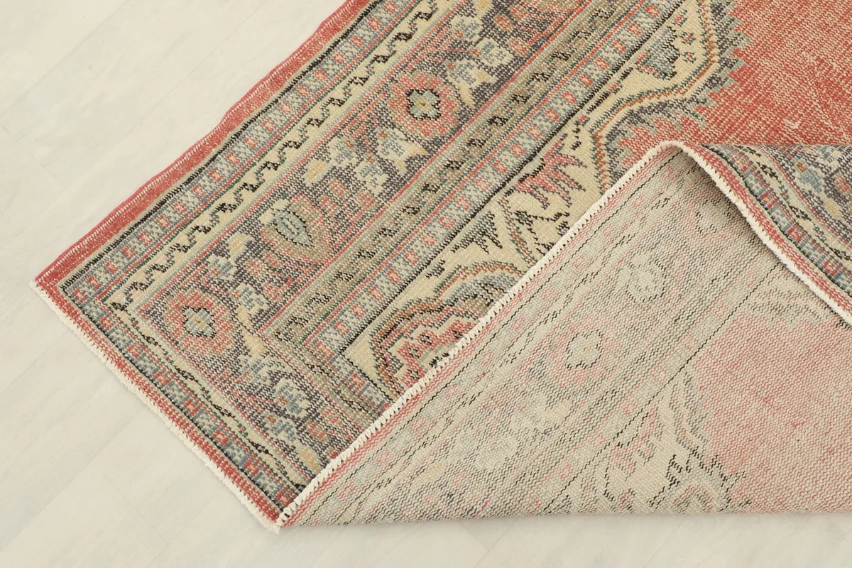 Corner of the rug folded to show the hand-knotted back and cotton foundation