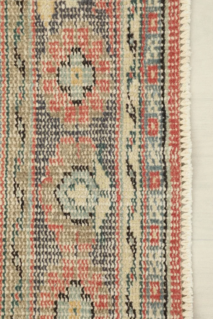 Detail of the rug's short, hand-finished fringes and edge binding