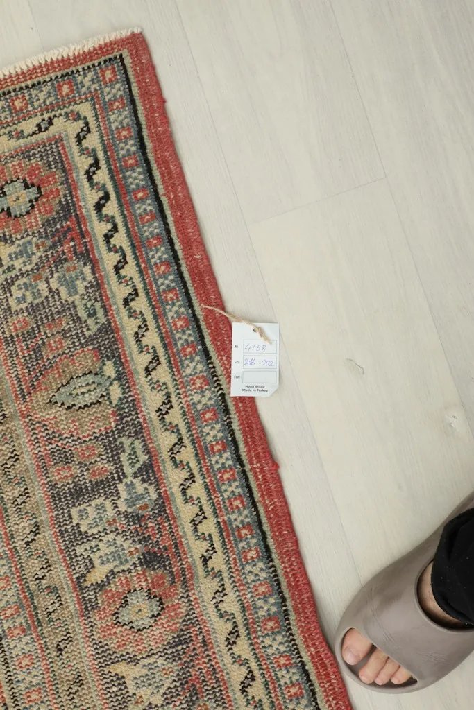 Close-up of the rug's edge with a size tag, next to a foot for scale