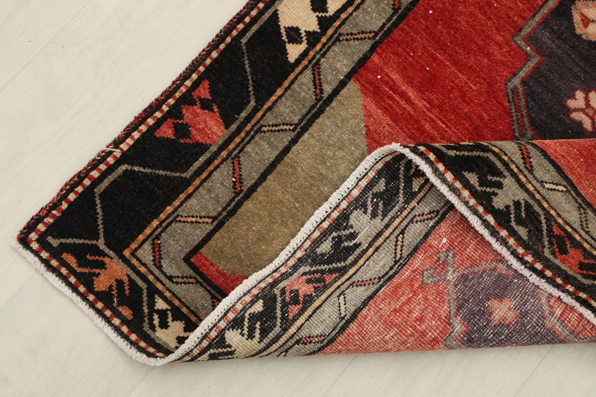 Corner of the runner rug folded back, revealing the reverse side and hand-knotted construction