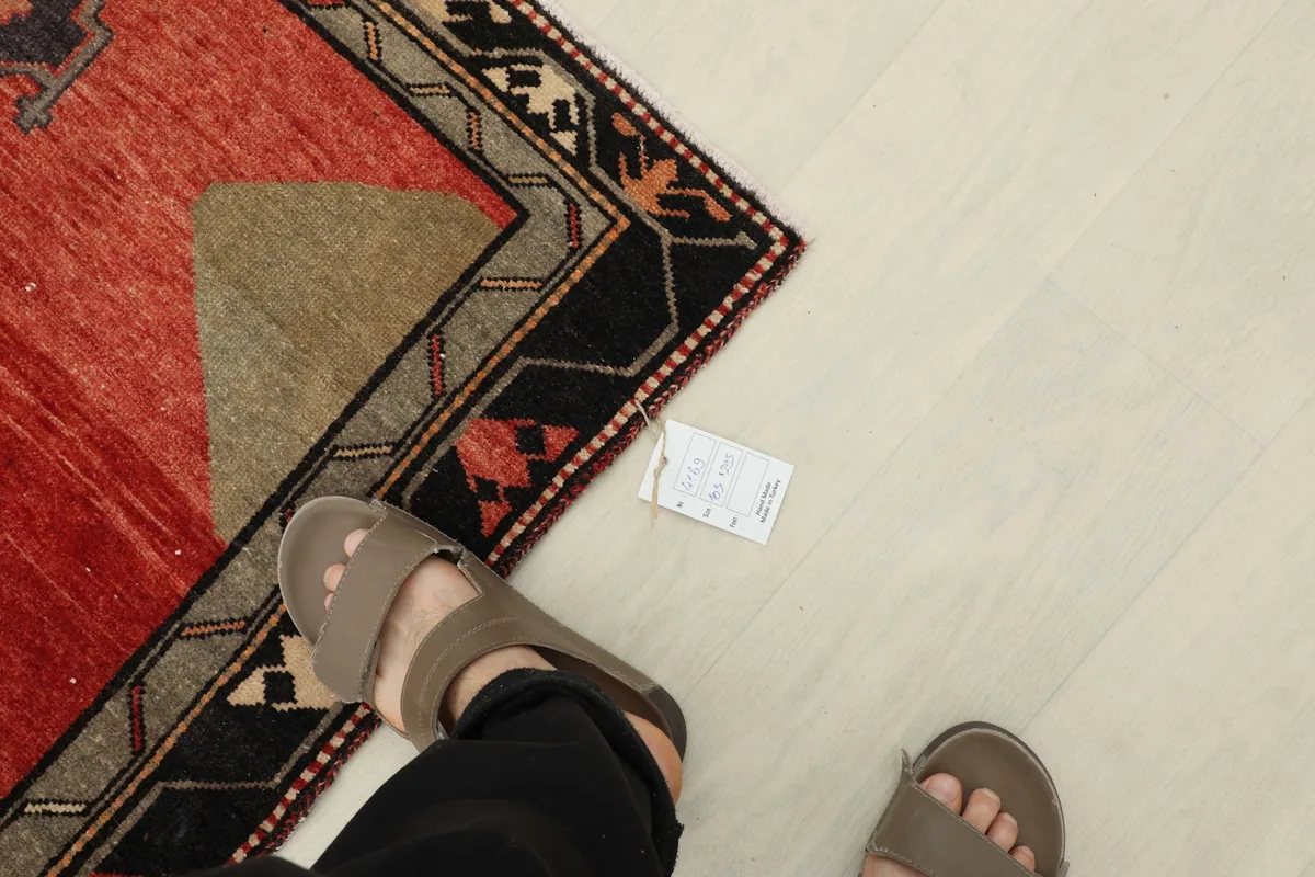 Overhead view of a person's feet next to the rug, showing a small tag