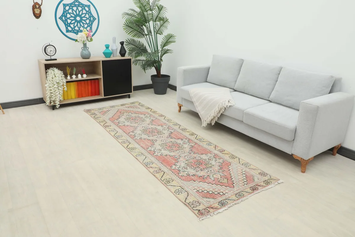 Vintage Anatolian runner rug laid out in a modern living space with a sofa and cabinet