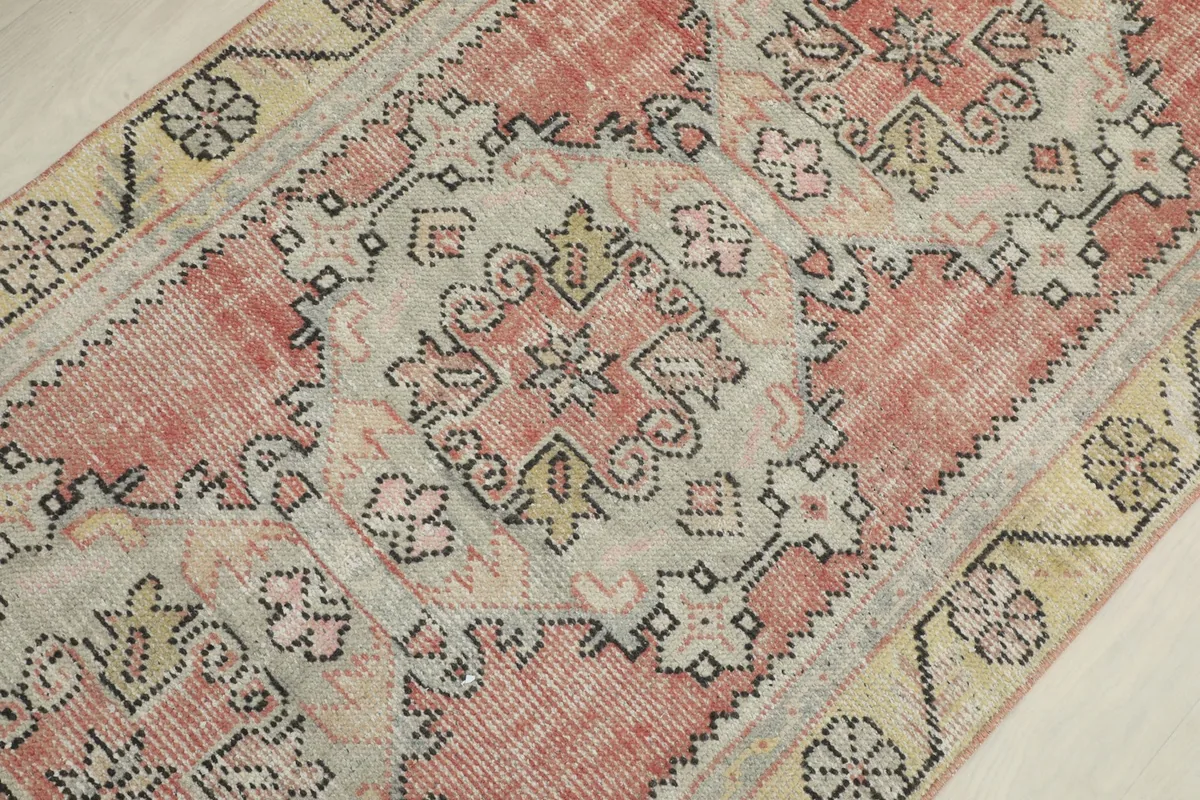 Detailed view of the central geometric motifs and faded rose and gray colors of the rug