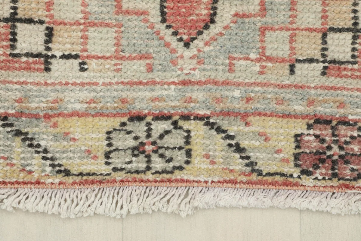 Close-up of the beige border with floral patterns and the short fringe of the vintage runner