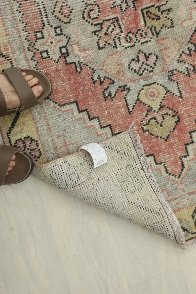 A person's feet on the rug, showing the scale and the texture of the vintage wool pile