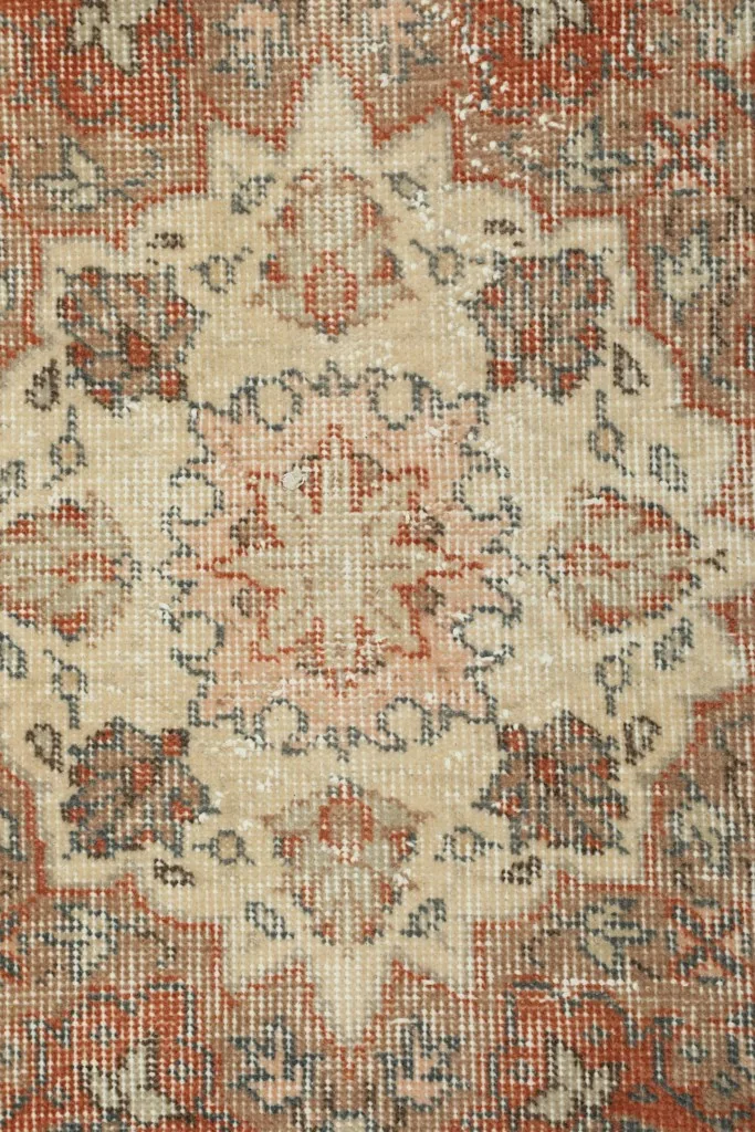 Close-up of the intricate floral patterns and color variations within the rust border and ivory elements
