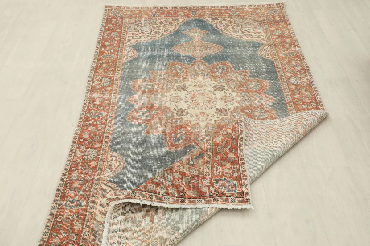 Rug partially folded, showcasing the full design from an elevated perspective and the back of the rug