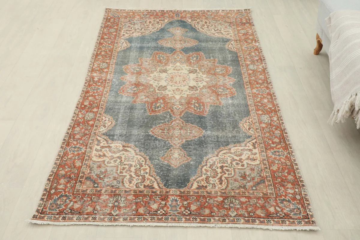 Full overhead view of the vintage blue and rust area rug, highlighting its complete design and colors