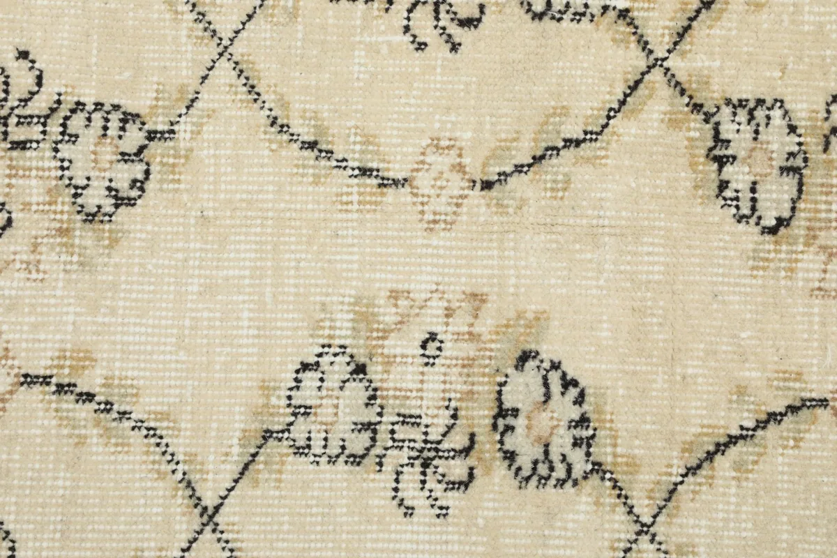 Detailed close-up of the hand-knotted wool pile and intricate gray and tan floral motifs