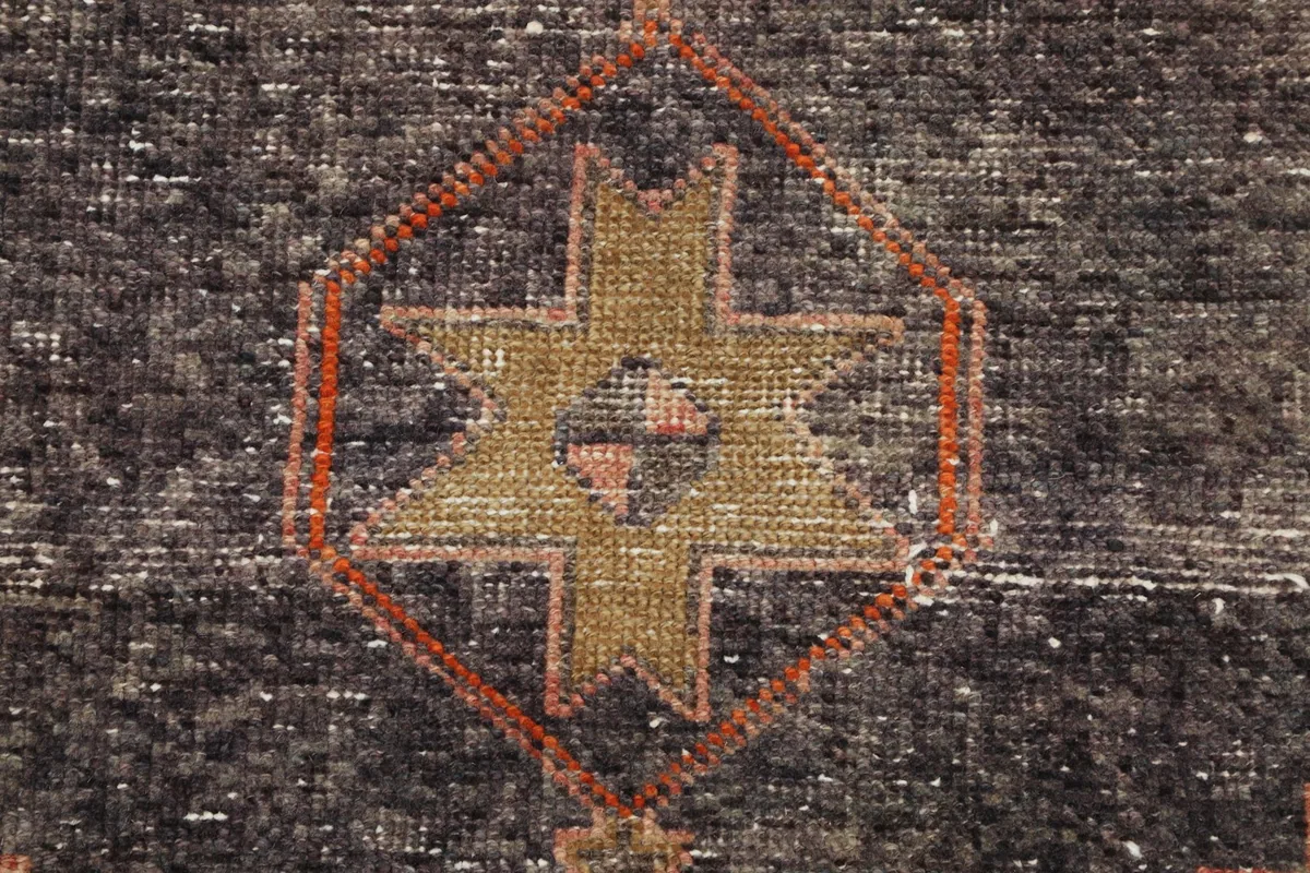 Extreme close-up of the central motif within a navy medallion, showing wool texture and knotting