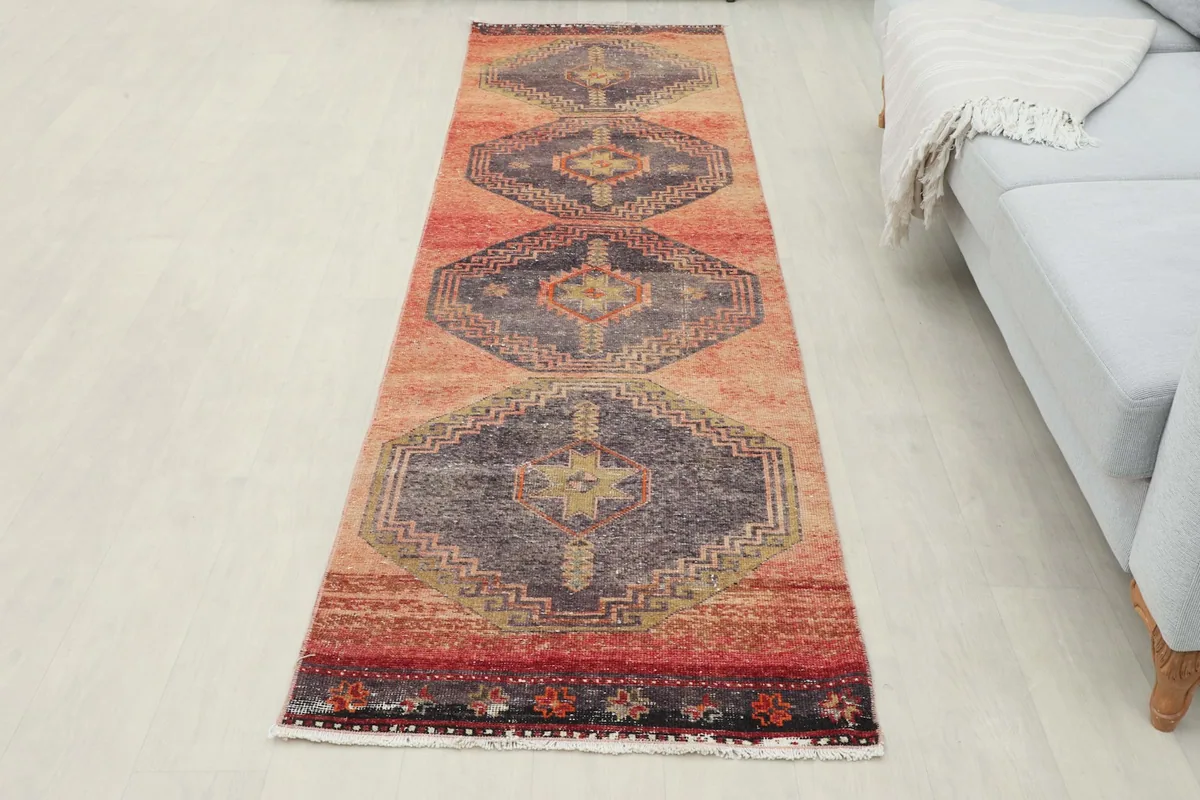 Full overhead view of the rust and navy runner rug laid out in a room, next to a gray sofa