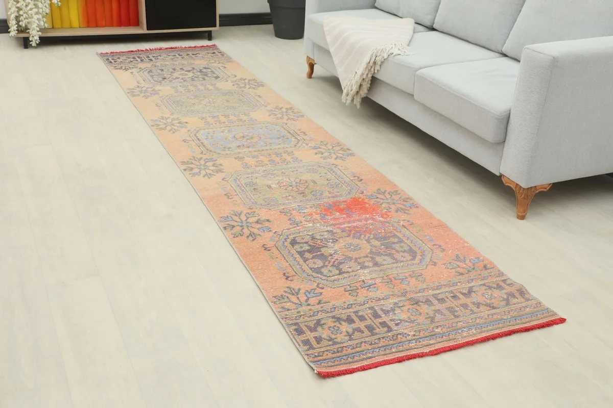 Overhead view of the blush geometric runner rug extending along a hallway next to a sofa