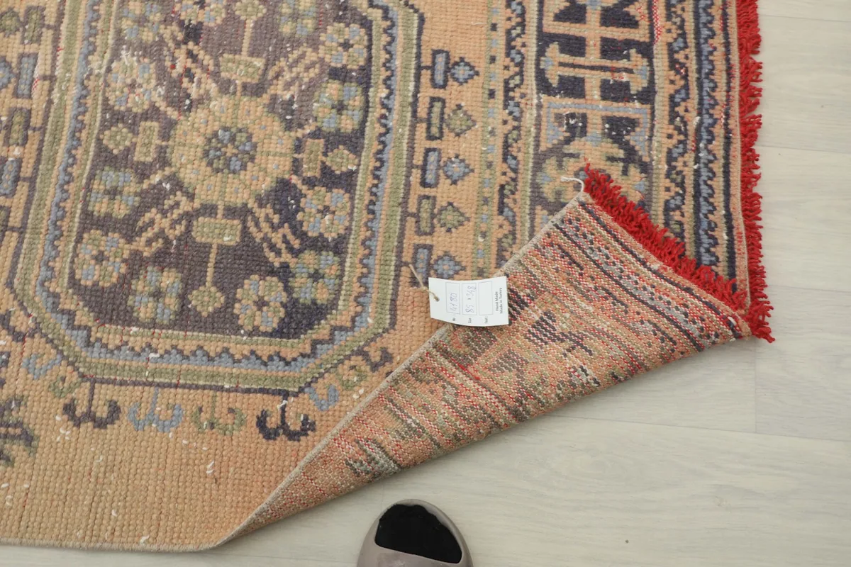 Close-up of a rug corner with a tag, showing the reverse side and hand-finished edge