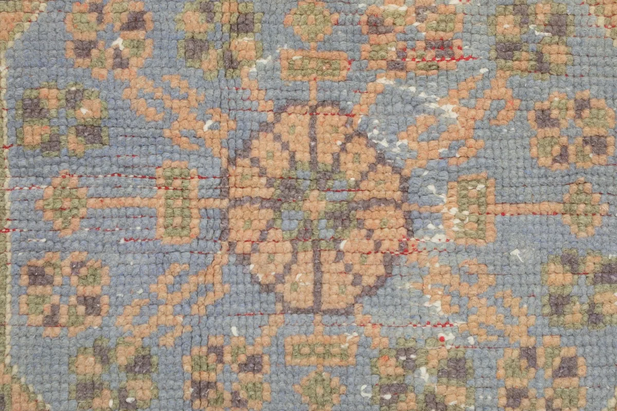 Macro view showing the low pile texture and intricate knotting of the blue and tan motifs